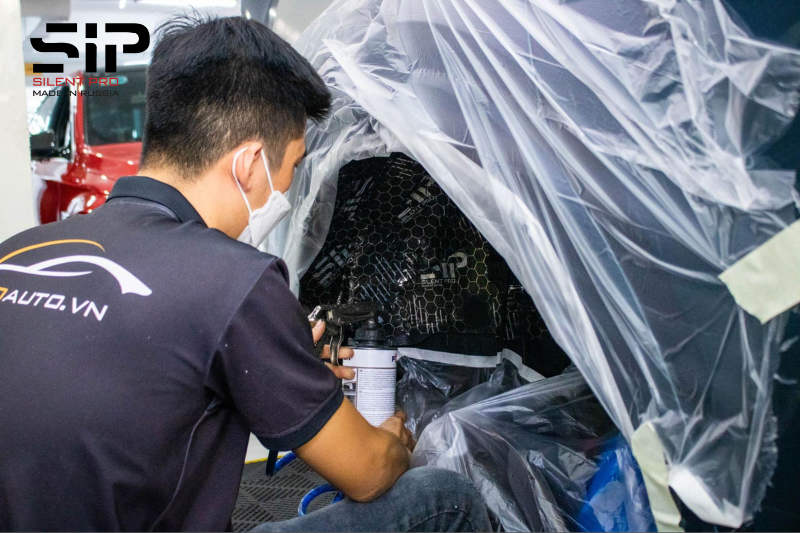 Kỹ thuật viên thi công xịt phủ gầm sau khi dán cách âm xe