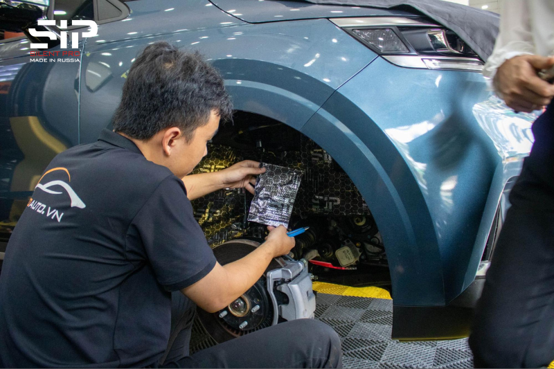 Kỹ thuật viên thi công dán cách âm SIP cho hốc bánh ngoài của xe