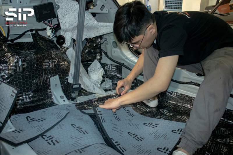 Kỹ thuật viên thi công dán tiêu âm SIP cho sàn xe 